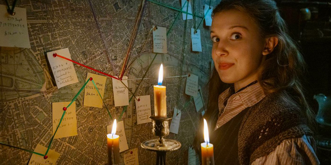 Enola Holmes (Millie Bobby Brown) holding a candle and smiling at the camera in Enola Holmes